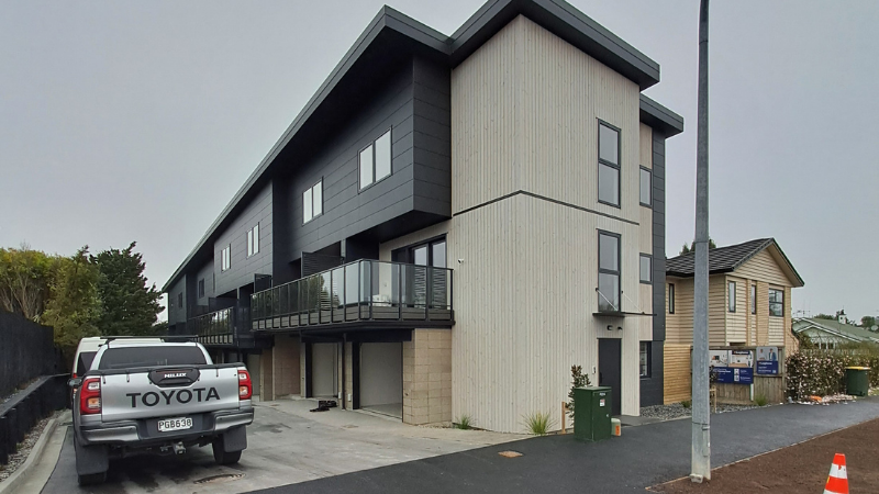 Street view of the 1 Manning Street townhouse development with glass balustrades, dark and light cladding, aluminium windows and ground-level garages.