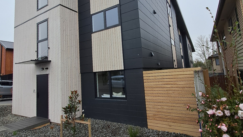 Side elevation of the 1 Manning Street multi-residential development, featuring contrasting light timber and dark cladding, black aluminium windows and landscaped gravel areas.