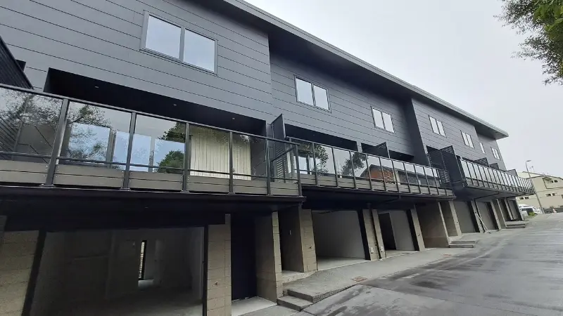 Exterior view of multi-residential townhouses at 1 Manning Street with dark cladding, balconies and aluminium windows and doors.