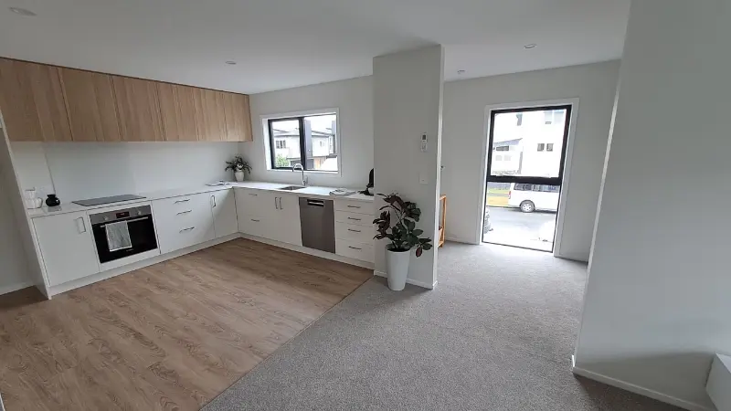 Open-plan kitchen and dining area with white cabinetry, timber finishes and a tall black aluminium window.
