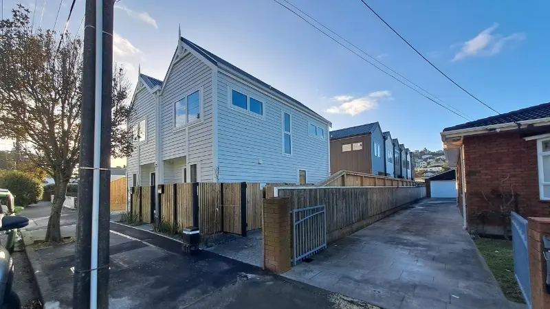 Street view of light-coloured and dark-clad townhouses at 21 Derwent Street with aluminium windows in varied configurations.