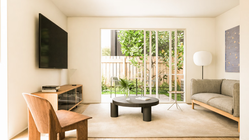 Bright living room with large aluminium stacker door opening to a landscaped courtyard, allowing abundant natural light into the home.