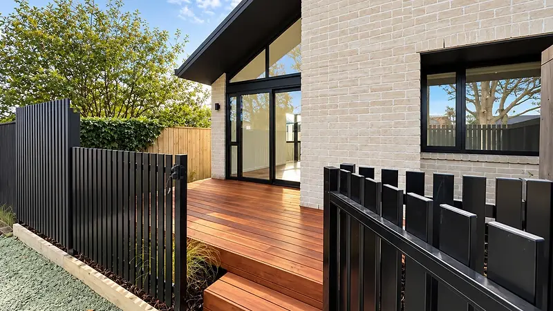 Timber deck at a 299 Levers Road home in Matua, Tauranga, with aluminium doors and raking gable glazing in white brick
