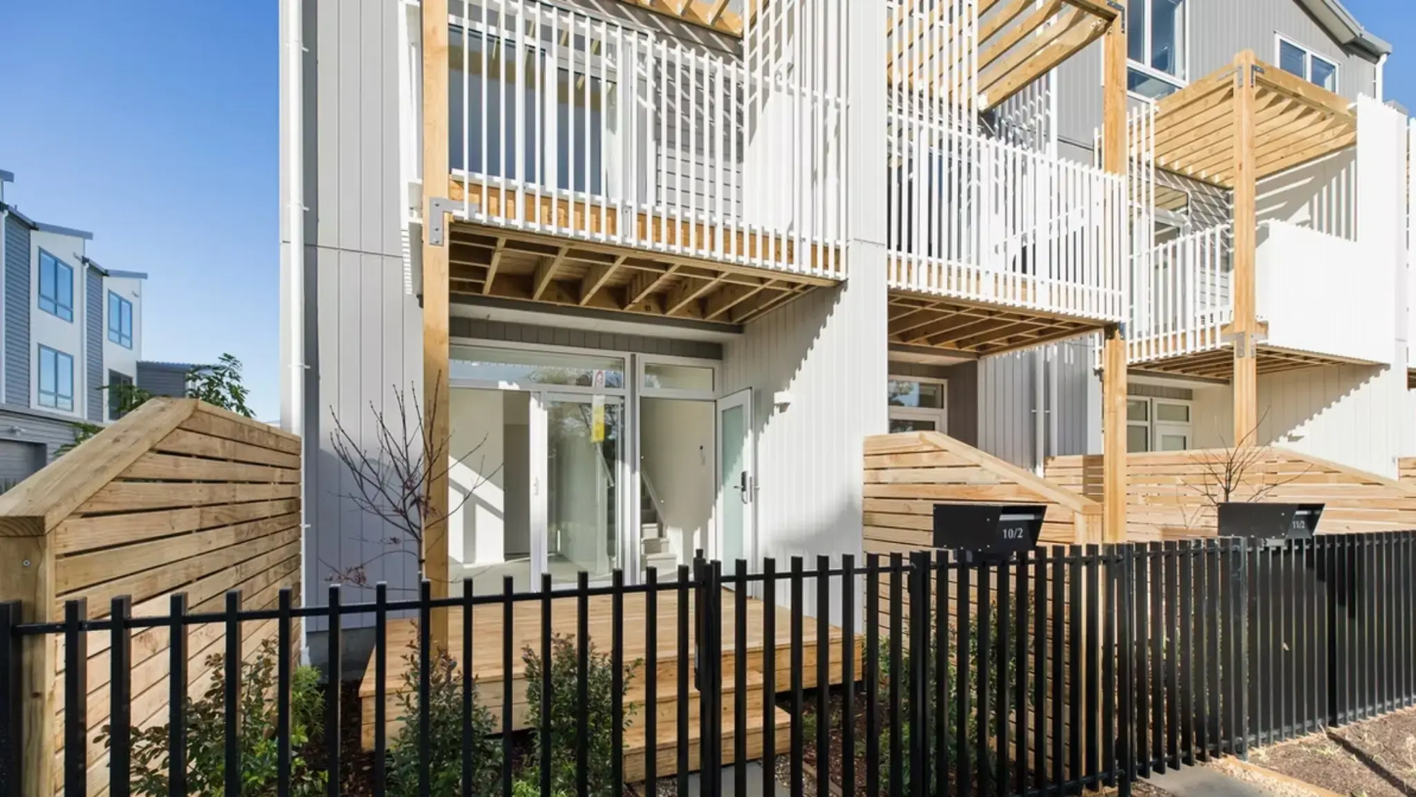Ground-floor townhouse patio with aluminium sliding doors, privacy fencing, and landscaped planting.