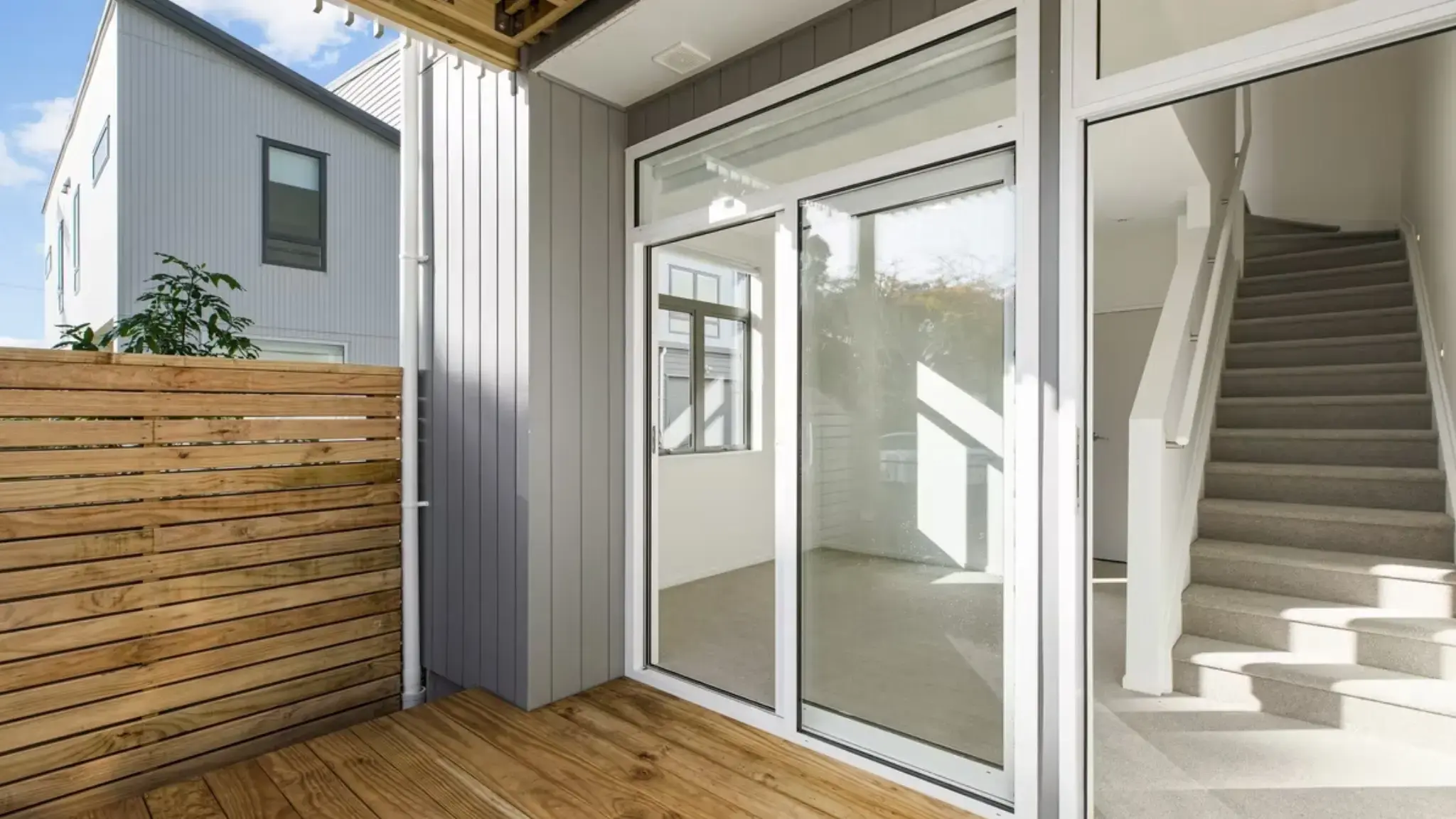 Covered outdoor deck featuring aluminium sliding door and glazed side panel leading into a townhouse interior.