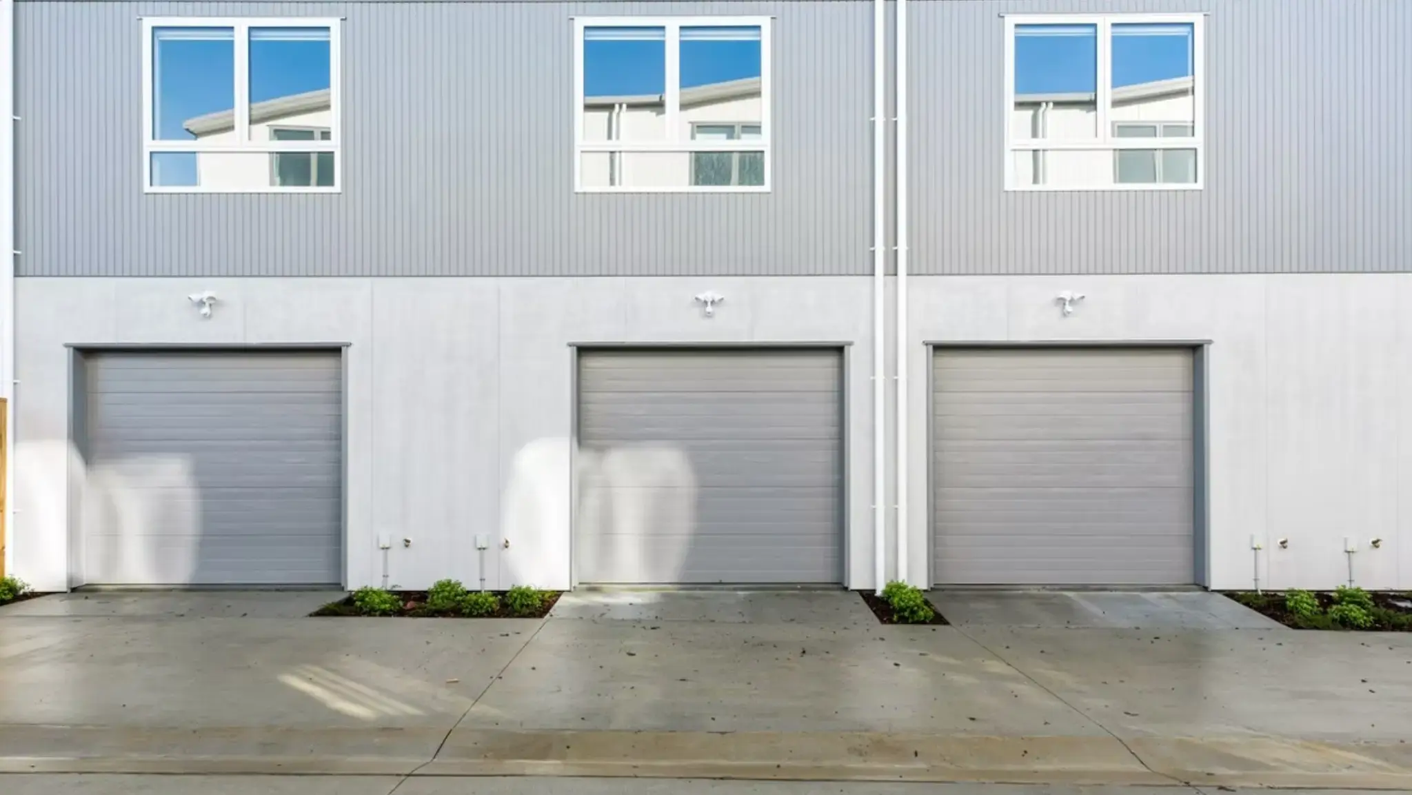 Rear elevation of townhouse garages featuring aluminium windows and contemporary exterior cladding.