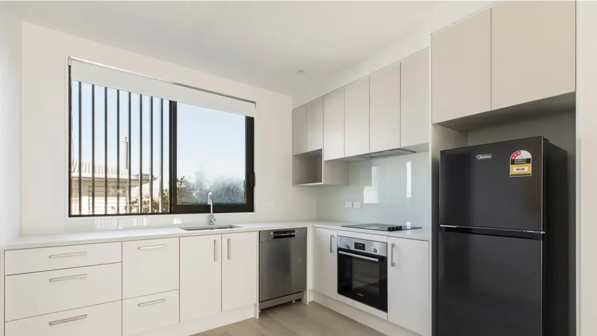 Modern townhouse kitchen featuring aluminium awning window, contemporary cabinetry, and open-plan layout.