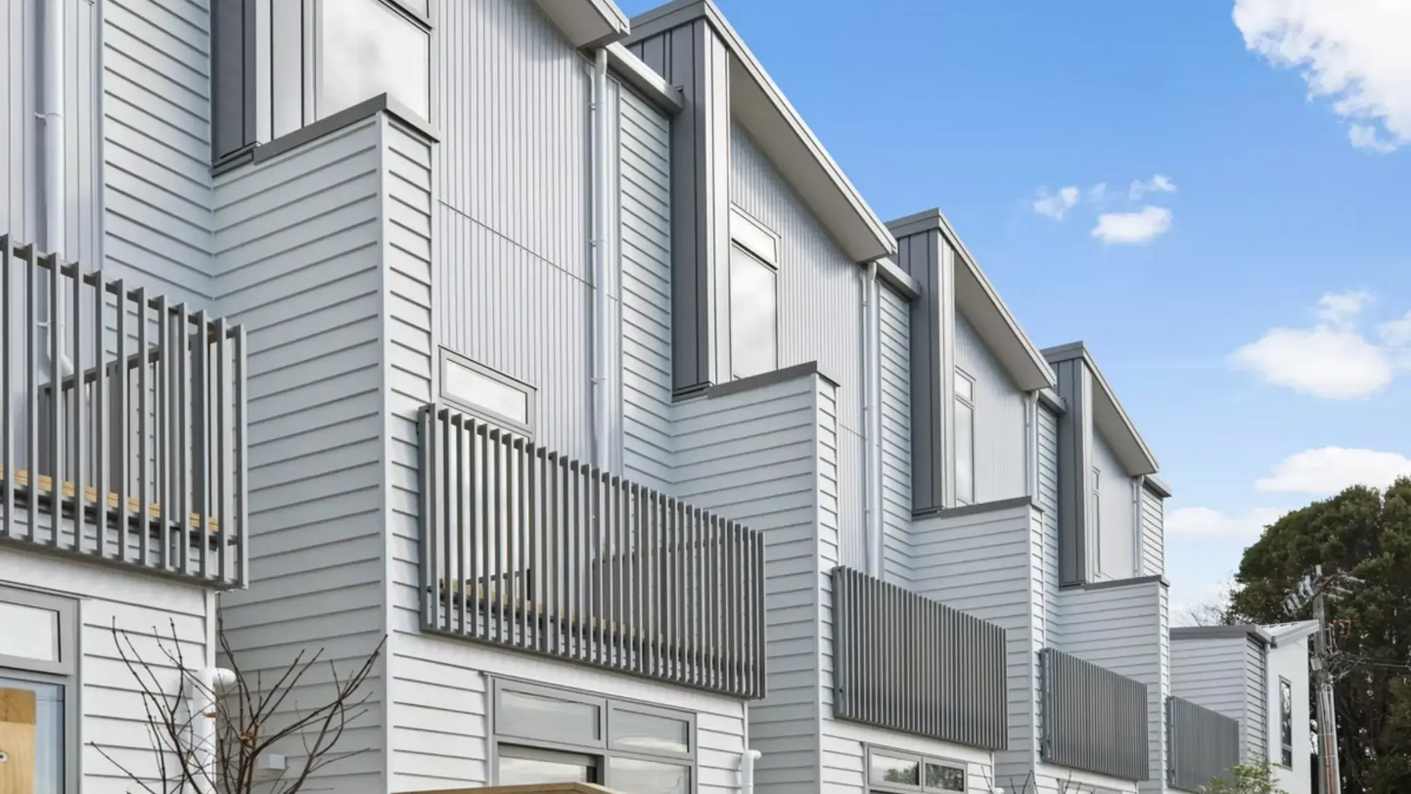 Side elevation of a contemporary townhouse development featuring aluminium windows, balconies, and modern cladding.