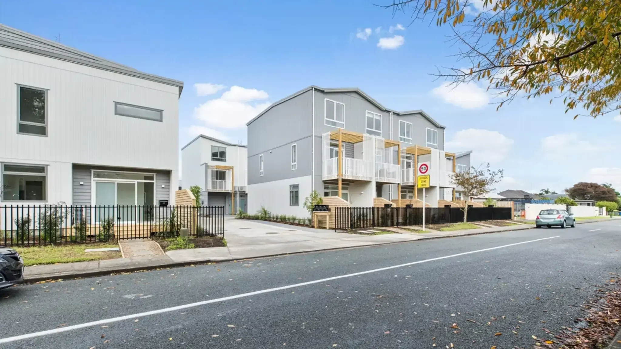 Street view of a multi-residential housing development with aluminium sliding doors, large windows, balconies, and landscaped streetscape.