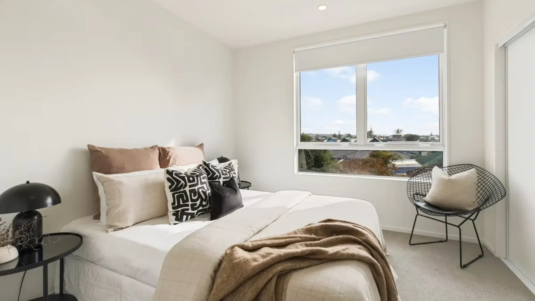 Bright townhouse bedroom featuring a large aluminium window providing natural light and elevated neighbourhood views.