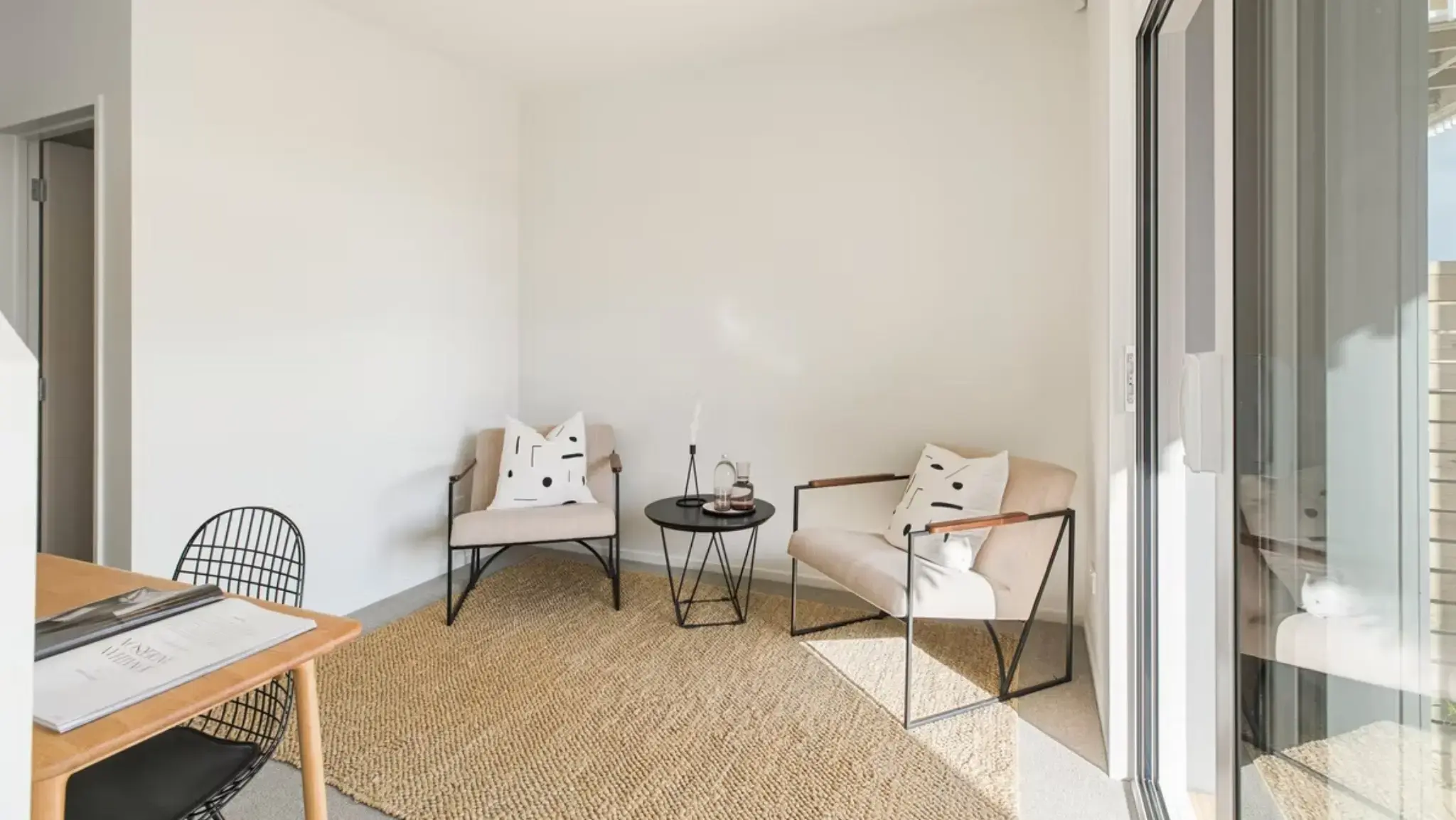 Townhouse living space with aluminium sliding door opening onto a covered outdoor deck and landscaped courtyard.