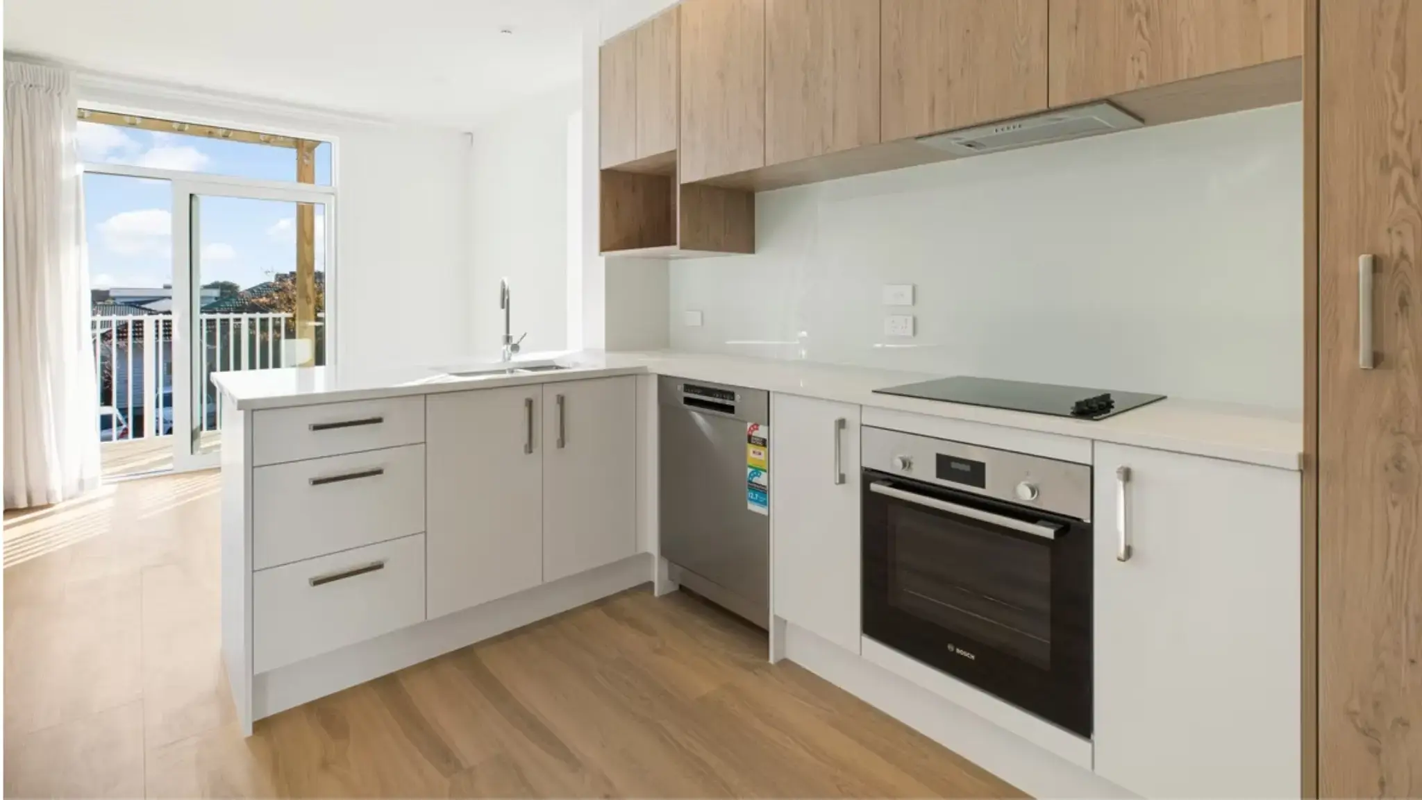 Modern townhouse kitchen with aluminium glazed door leading to an outdoor balcony and contemporary cabinetry.