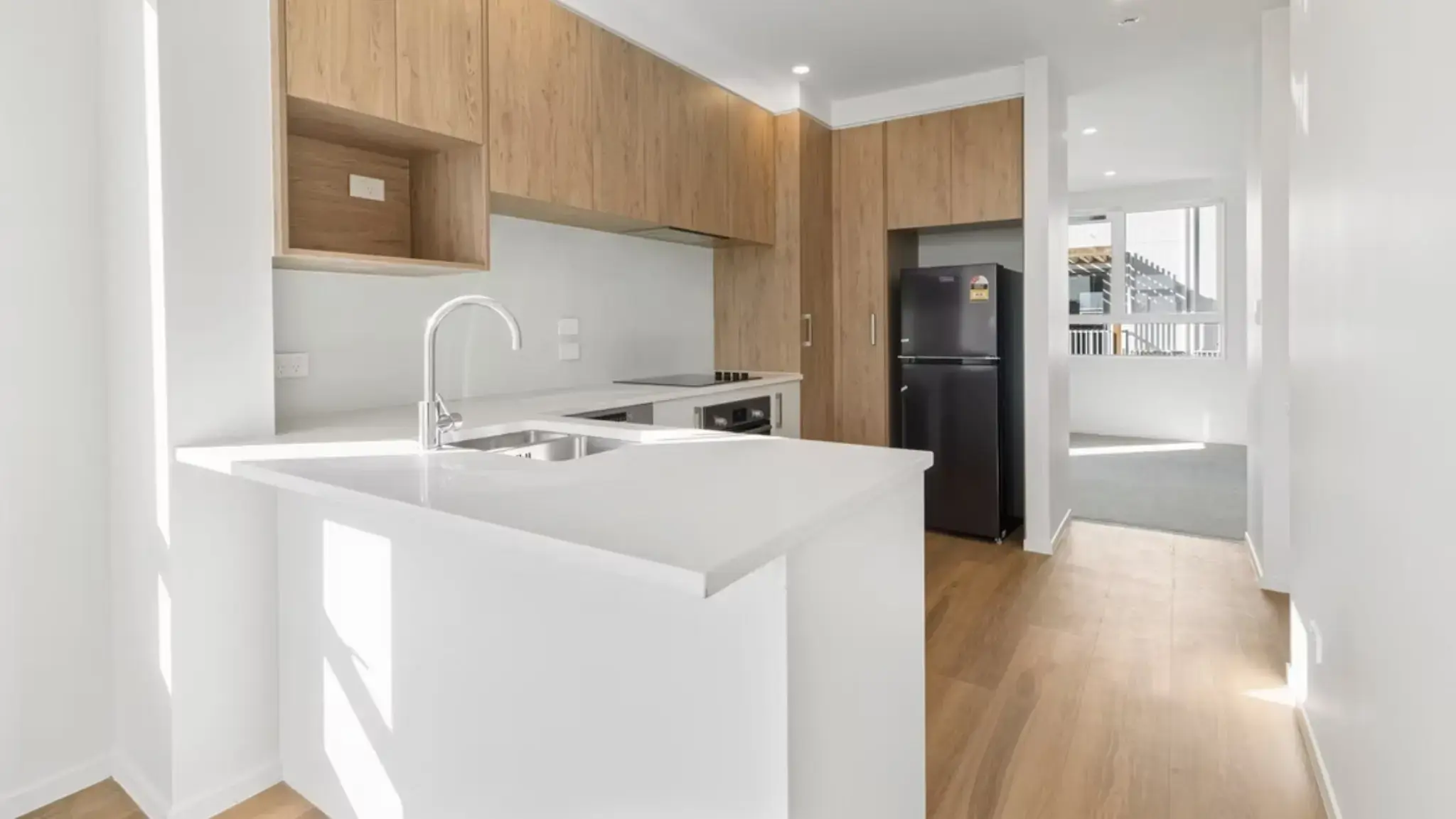 Open-plan kitchen featuring modern cabinetry, aluminium windows, and natural light throughout the townhouse interior.