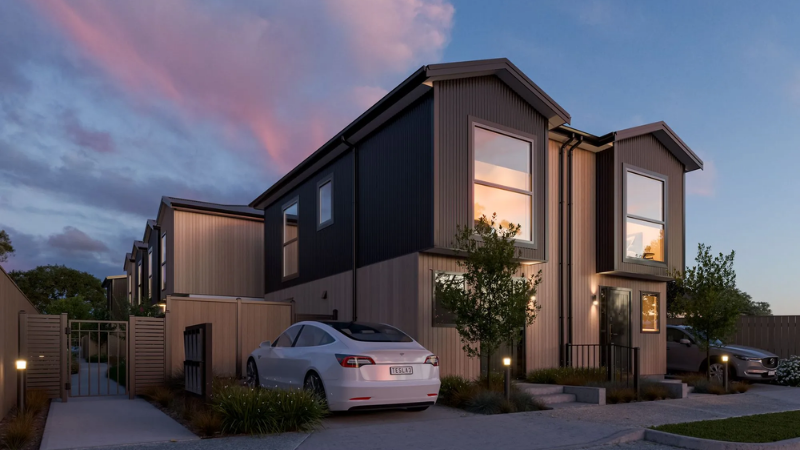 Contemporary townhouse development at dusk with illuminated interiors, large aluminium windows, landscaped pathways, and parked electric vehicle.
