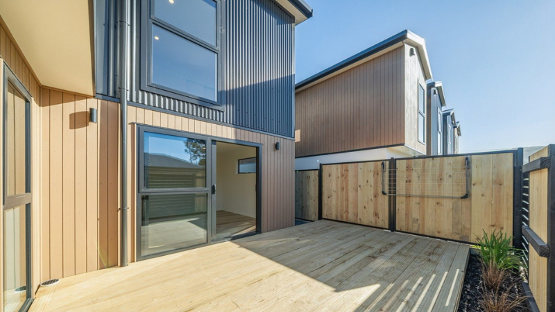 Rear townhouse courtyard with timber decking, dark aluminium windows and a wide sliding door.
