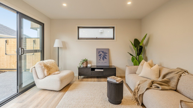 Styled living room with a large aluminium sliding door, high-level window, sofa, armchair and indoor plants.