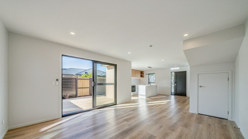 Spacious open-plan living area with a large dark-framed aluminium sliding door opening to a private courtyard.