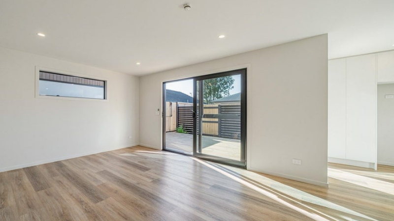 Modern living room with a wide aluminium sliding door, high-level window and timber-look flooring.
