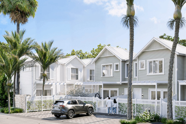 Contemporary white townhouse development with pitched rooflines, tropical landscaping, white fencing, and modern aluminium windows and doors.