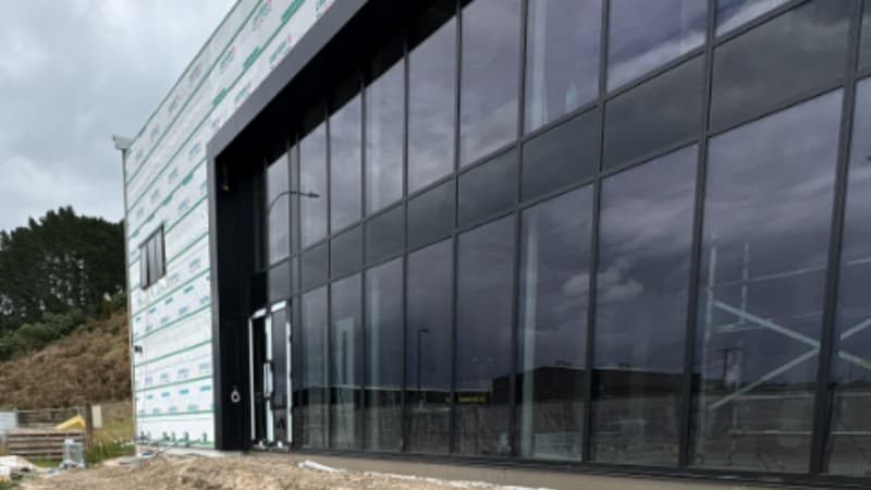 Commercial building with large aluminium window panels under cloudy skies, showcasing flushglaze façade system.