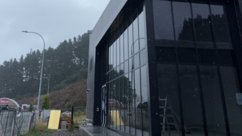 Modern commercial building with aluminium glazing system in wet weather, showing reflections and sealed façade performance.