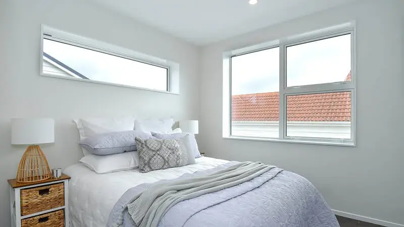 Bedroom at Hollard Grove, Avalon, Lower Hutt, with a long highlight window above the bed and a multi-pane aluminium window to the side