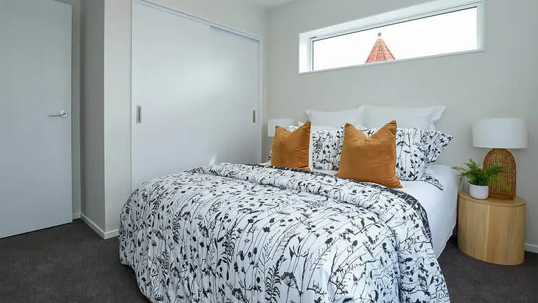 Bedroom at Hollard Grove, Avalon, Lower Hutt, with a highlight window above the bed and a built-in wardrobe