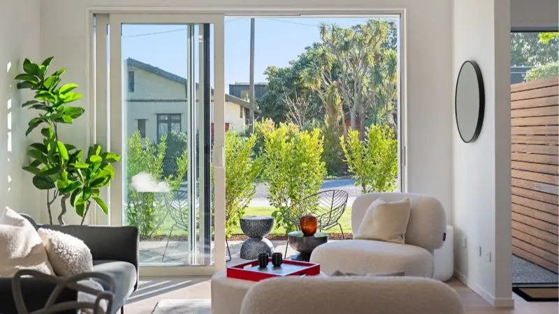 Living room opening onto an outdoor patio through large aluminium sliding doors.