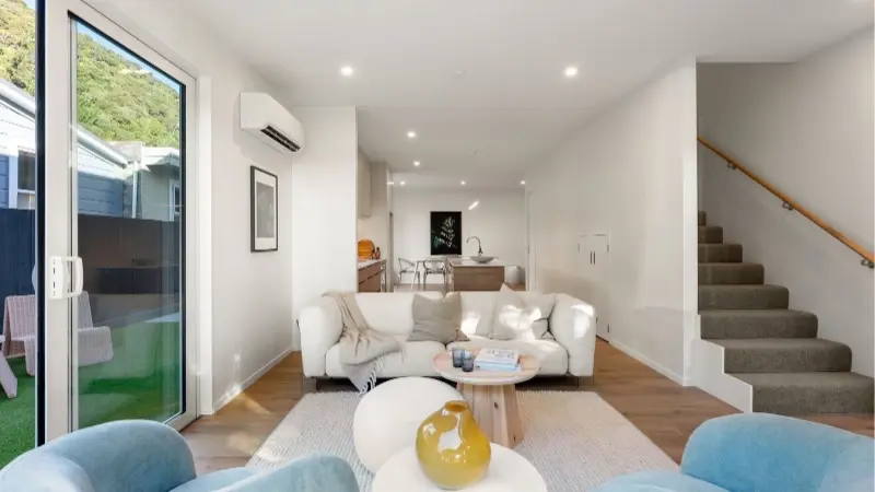 Open plan living space with aluminium sliding doors, large windows and staircase.